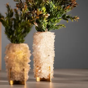 Sculptural Medium Vase Desiree II in white quartz next to larger matching vase, both with green plants, on white background.