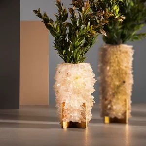 Sculptural Small Vase Desiree II in white quartz next to larger matching vase, both with green plants, on white background.