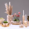Composition of white quartz vases, gold-plated candelabras and centerpieces with flowers, candles, and wheat grass on neutral background