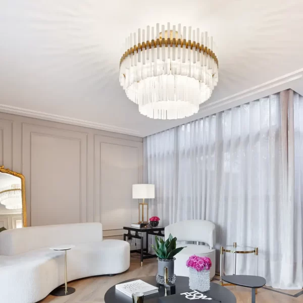 Living room featuring the Paris Deluxe Chandelier with Warm Gold Leaf finish above a side table, paired with a Dubai Table Lamp in the background.