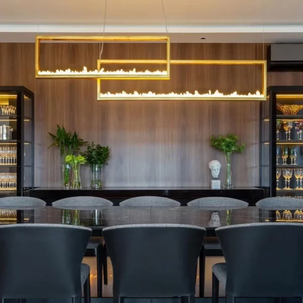 Pair of horizontal quartz pendant trios in warm gold leaf over dining table, one 35.4" and the other 70.9".