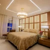 Master suite bedroom featuring two natural Stone Dubai table lights and a chandelier with adjustable cables.
