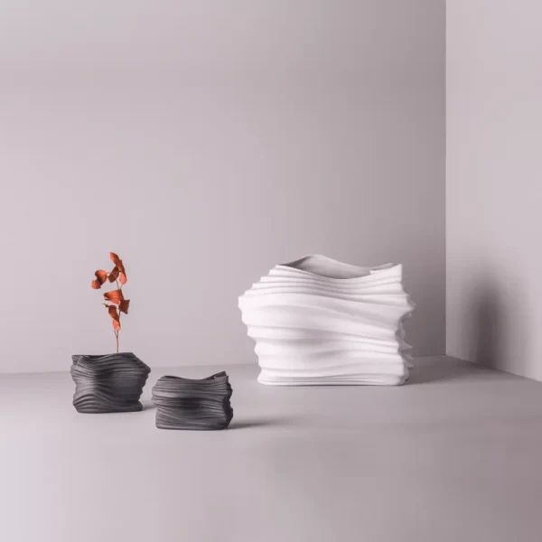 Three modern matte white and matte black porcelains photographed in a studio with neutral tones.