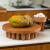Large wooden centerpiece with papaya on top and a bowl with eggs on a white granite countertop in the kitchen.