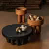 Black small centerpiece and a pair of wooden bowls decorated with mushrooms on a wooden table.