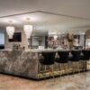 Distant view of an American kitchen with a Petit London Natural Stone Lighting Fixture above a central island.