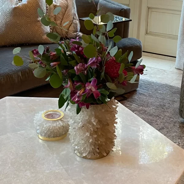 A Quartz Flower Pot with flowers placed on a coffee table in a luxurious living room. The vase features a hand-gilded silver leaf finish, enhancing its elegant appearance.