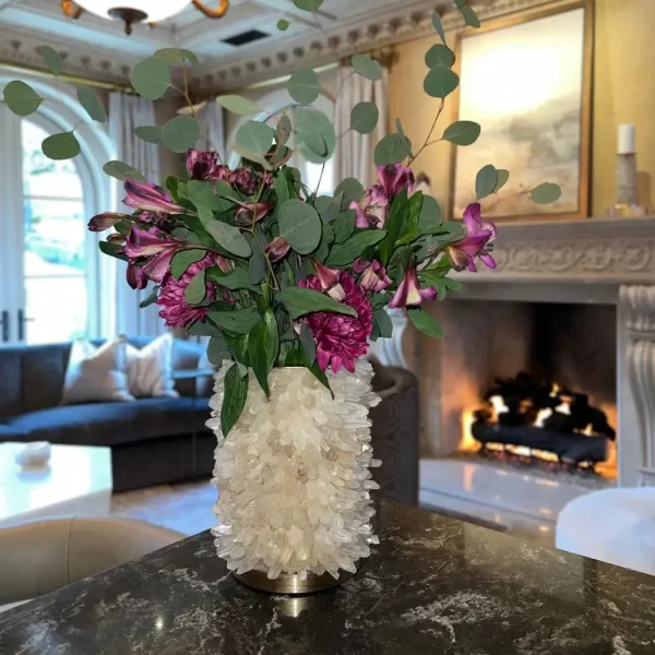 Close-up at A Quartz Flower Pot with flowers placed on a coffee table in a luxurious living room. The vase features a hand-gilded silver leaf finish, enhancing its elegant appearance.