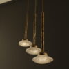 Three Aurah Rock pendant lights with a gold finish and quartz diffusers glowing softly, designed for refined decorative lighting.
