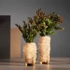 Close-up at a pair of Sculptural Small Vases, White Quartz, Desiree, in small and medium sizes, adorned with lush foliage. The vases feature a fine Brazilian craftsmanship with an accurate selection of Crystal Quartz, perfect for interior design projects.