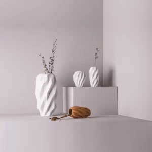 Studio composition with three matte white Plisan Geometric Vases and one clay color vase.