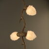 Close-up detail of the Quartz Cascade Pendant - Branches IX showing a glowing cluster of quartz crystal lights on the bronze twig-like frame.