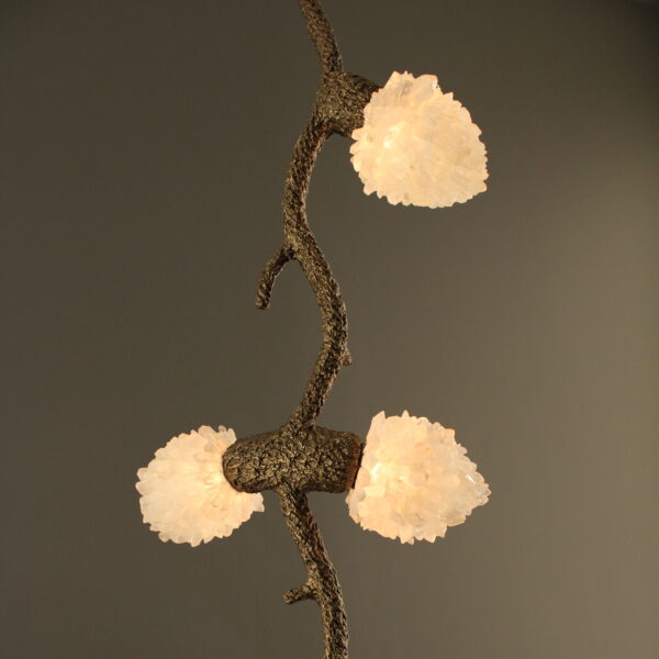 Close-up detail of the Quartz Cascade Pendant - Branches IX showing a glowing cluster of quartz crystal lights on the bronze twig-like frame.