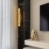 Quartz LED Wall Lamp New York 24″ with warm silver leaf finish, contrasting against a black marble wall in the TV room, highlighting the sophisticated design