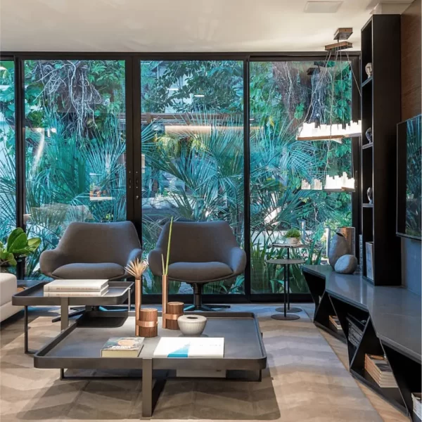 Pair of Selenite LED Pendant Lights Lisbon in Dark Silver Leaf Finish, Enhancing a TV Room with a Glass Wall Overlooking a Lush Green Garden