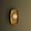 Wall light with a golden textured base and a translucent spherical crystal, combining raw materials with refined craftsmanship.