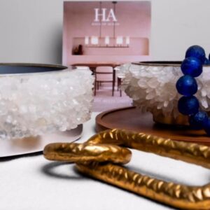 Close-up of a white quartz centerpiece with silver leaf details, accompanied by blue beads and gold decorative chains on a modern minimalist table setting.