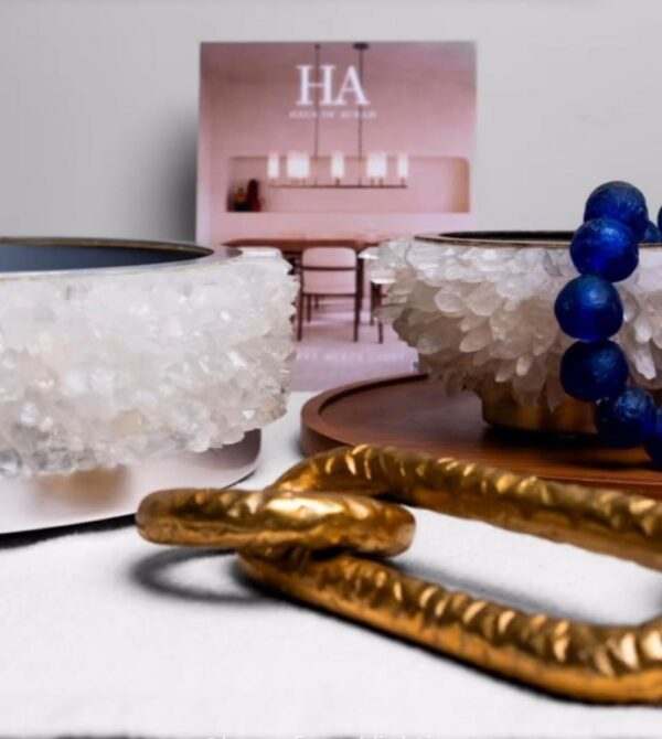 Close-up of a white quartz centerpiece with silver leaf details, accompanied by blue beads and gold decorative chains on a modern minimalist table setting.