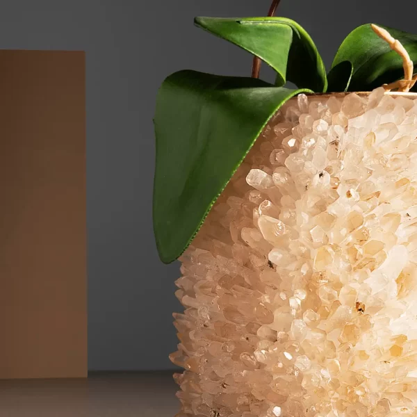 Close-up of a White Quartz Vase with warm gold leaf finish, adorned with green foliage, showcasing detailed craftsmanship.