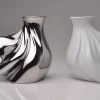 Pair of porcelain vases, one in silver and one in matte white, on a white background.